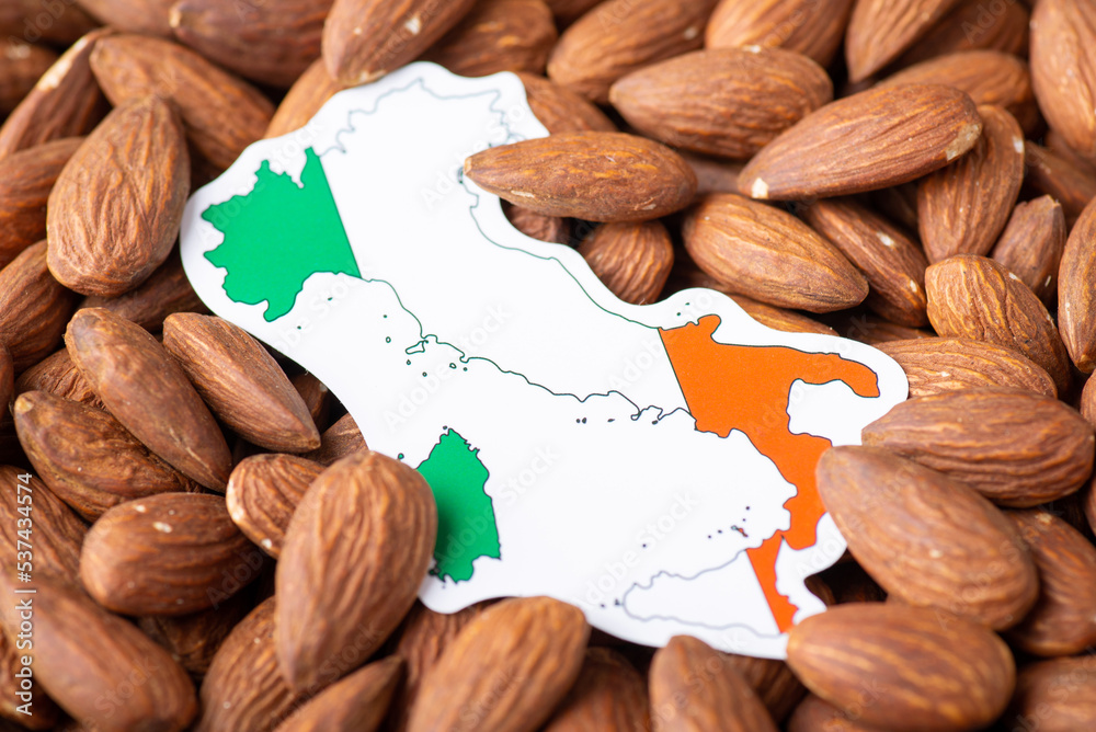 Poster Small paper map and flag of Italy on almond nuts. Concept of growing almond in Italy, origin of almond