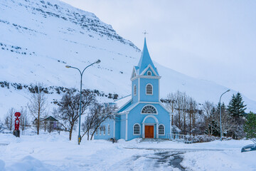 Fototapeta na wymiar Regnboga Vegur or Rainbow Road and Seyðisfjarðarkirkja blue wooden church during winter evening at Seydisfjordur , Fjord towns in Eastern Coast Iceland : 18 March 2020