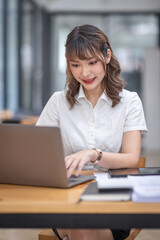 Young Business Asian woman using calculator and laptop for doing math finance on an workplace, tax, report, accounting, statistics, and analytical research concept.