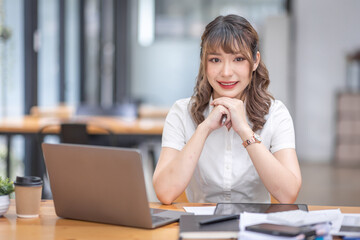 Young Business Asian woman using calculator and laptop for doing math finance on an workplace, tax, report, accounting, statistics, and analytical research concept.