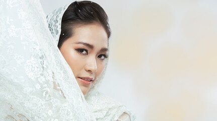 Face shot 20s Asian Woman has beautiful wedding clean face skin. Lace hijab cloth female feel happy smile fashion vintage poses over grey background isolated copy space