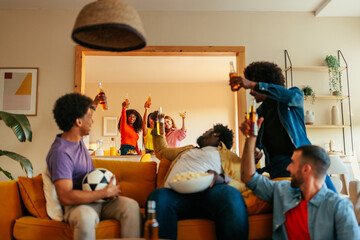 Friends watching soccer and toasting with drinks.