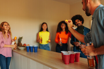 Friends playing beer pong at party.