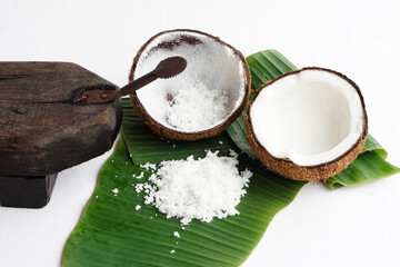 Closeup Coconut grater tool, coconut shell on green banana leaves, prepare coconut milk for food or dessert. Concept Thai traditional cooking method.  © Sanhanat