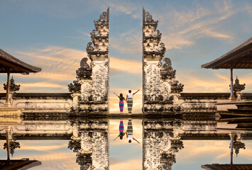 Happy Asian couple standing in the gates of the temple of heaven and holding each other's hand. Perfect honeymoon idea. Lempuyang Luhur Temple in Bali, Indonesia. - obrazy, fototapety, plakaty