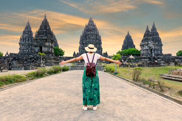 Indonesia, Prambanan- young girl with hat standing with open arms looking  Prambanan temple during...