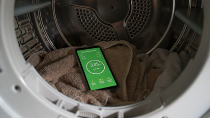 A smart phone with energy consumption app displaying energy usage in a laundry setting