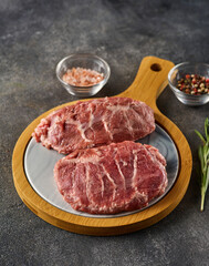 Fresh raw pork cheeks with salt and pepper. Grey background