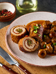 Pork roulade with pickles and bacon, served with fried mushrooms and green onions