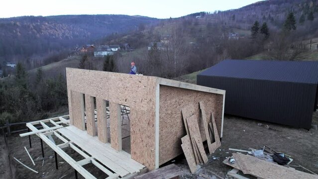 Aerial view of wooden frame house on pile foundation in the Scandinavian style barnhouse under construction in the mountains.