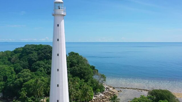 aerial of white lighthouse on remote tropical island in belitung indonsia on sunny summer day