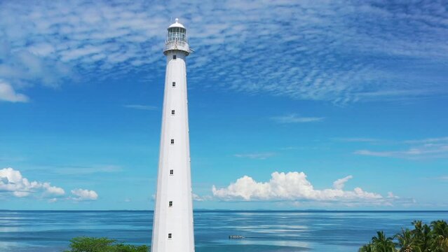 aerial camera panning up at white lighthouse in belitung indonesia with beautiful tropical blue water