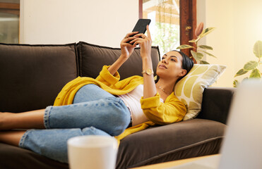 Relax woman on her phone with social media while on the sofa in house. Content female browsing internet with app while relaxing on the couch at home reading news, post and internet or web