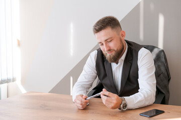 Portrait bearded business man sitting in office meditating holding pen in his hands and considering a business concept for the future.