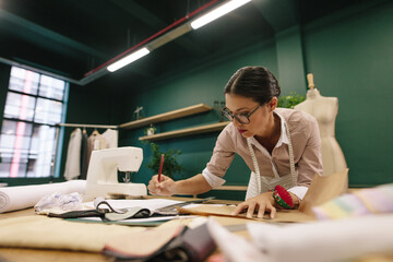 Female fashion designer drawing a design sketch in her workshop - Powered by Adobe