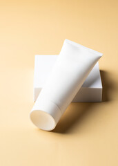 Abstract white cosmetice tube on the podium on beige background with shadow. Moke up and showplace for brand
