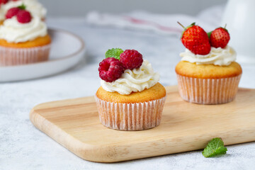 Cupcake with raspberries on a wooden board