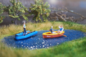 Miniature people who are doing boat & fishing activities