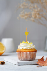 Cupcake with yellow heart on the table in autumn