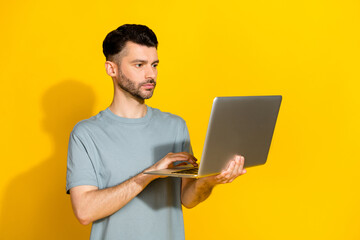 Photo of serious confident professional businessman hold new netbook typing programmer it development owner isolated on bright yellow color background