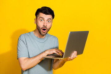 Photo of young impressed brunet hair bristle beard open mouth unexpected look you shocked breaking news information laptop isolated on yellow color background