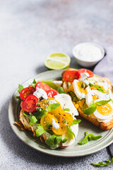 Variety of croissant sandwiches with tomato, cucumber, mozzarella cheese, eggs and mashed avocado with mint and arugula. Open savory sandwiches. Tasty healthy breakfast.