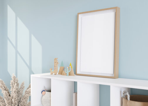 Empty vertical picture frame standing on sideboard in modern child room. Frame mock up in contemporary style. Free, copy space for picture, poster. Toys, pampas grass. Close up view. 3D rendering.