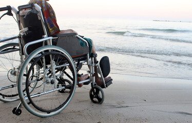 Fototapeta premium old man on a wheelchair looks at the sea from the beach