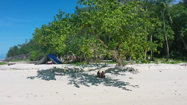 aerial of couple camping on a beautiful white sand beach in belitung Indonesia