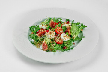 Salad with goat cheese and figs in a white plate on a white tablecloth. Close-up, selective focus