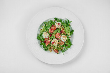 Salad with goat cheese and figs in a white plate on a white tablecloth. Close-up, selective focus