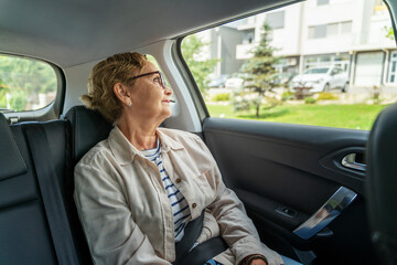 Beautiful happy senior woman sitting in the passenger seat in the car enjoying the ride