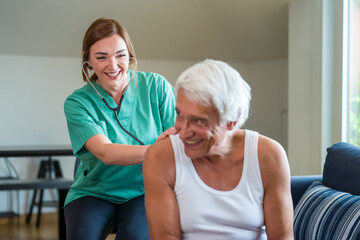 Young caregiver helping senior man at home and checking vital parameters, nurse assisting her old man patient at nursing home, friendly nursing home lady doctor with senior