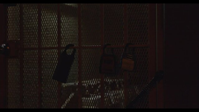 Close-up video of the locked fenced door with three different size locks hanging from it