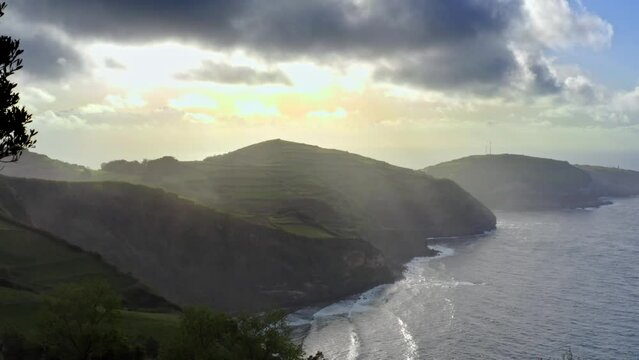 Majestic sunlit atlantic ocean coastline with sunrays in Azores, aerial.