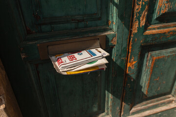 Vintage Newspaper sticking out of the mail in the door. Vintage green antique door with mail and...