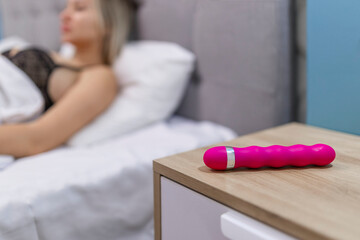 Young woman holding sex toy dildo vibrator in bed