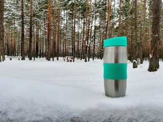 green travel mug bottle on white snow table