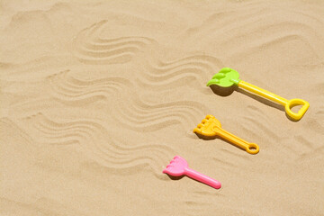 Fototapeta na wymiar Plastic rakes on sand, space for text. Beach toys