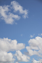 A piece of a blue sky with many clouds around. Midday cloudscape in the summer sky.