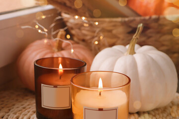 Scented candles and pumpkins on window sill indoors