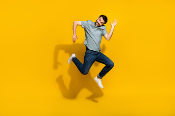 Fototapeta na wymiar Full length portrait of satisfied glad young person jumping arms make moves isolated on yellow color background