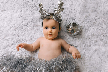 Baby with Christmas decoration lying on white background. New year and Christmas concept