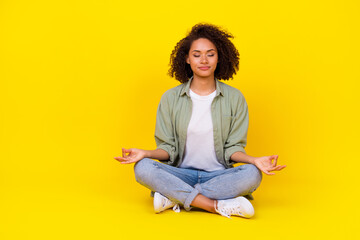 Full length photo of cute young lady curly hair sit lotus pose enjoy meditate wear trendy khaki clothes isolated on yellow color background - obrazy, fototapety, plakaty