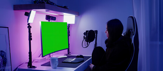 GREEN SCREEN CHORMA KEY Korean female gamer streamer putting on headphones, playing online games and streaming from home © supamotion