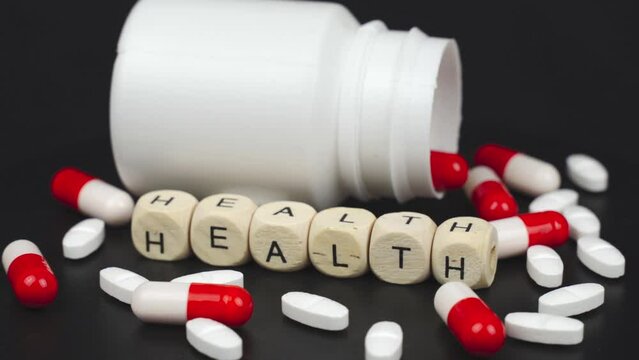 Medical concept. On a rotating surface are capsules, a jar, tablets and cubes with the inscription - Health. The surface is rotating. Close-up.