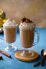 Latte with cinnamon in glass cup with cream. on blue background. Autumn comfort, warming drink. Mood lifestyle drink photo.
