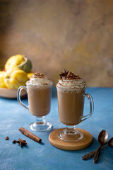 Latte with cinnamon in glass cup with cream. on blue background. Autumn comfort, warming drink. Mood lifestyle drink photo.