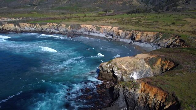 Natural Aerial drone flying over Big Sur California coast beach. The ocean clouds sky sun sunny waves crashing. Travel view scene peak weather wave. Rocky formations. High quality 4k footage.