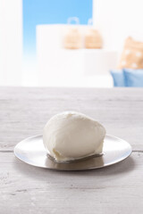 mozzarella on silver round plate, resting on white wooden table
